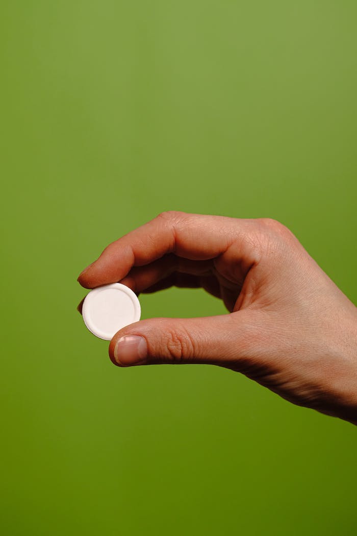 A human hand holding a plastic chip against a vibrant green background, showcasing simplicity and focus.