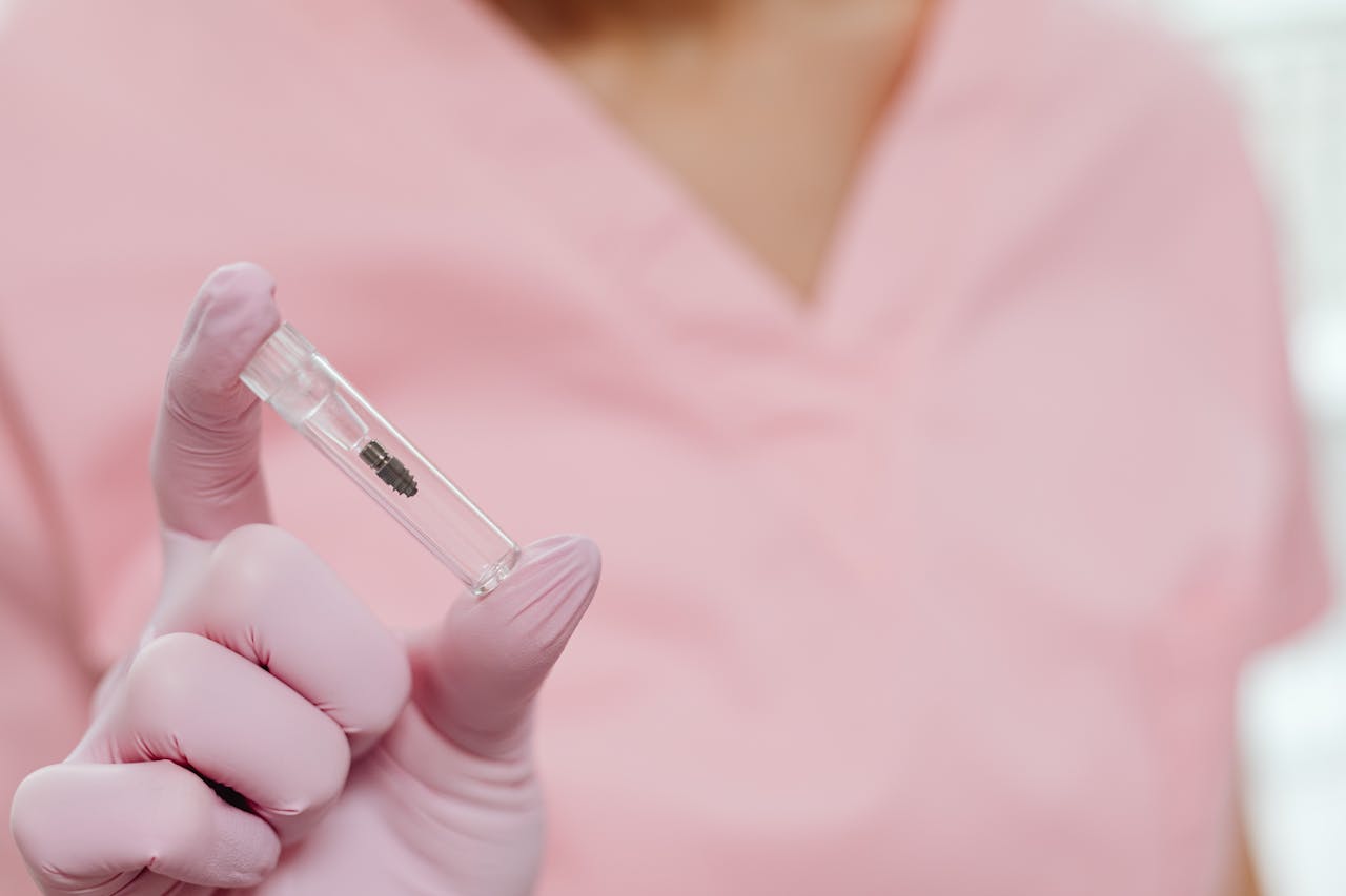 Close-up of a nurse holding a dental implant in a sterile environment.